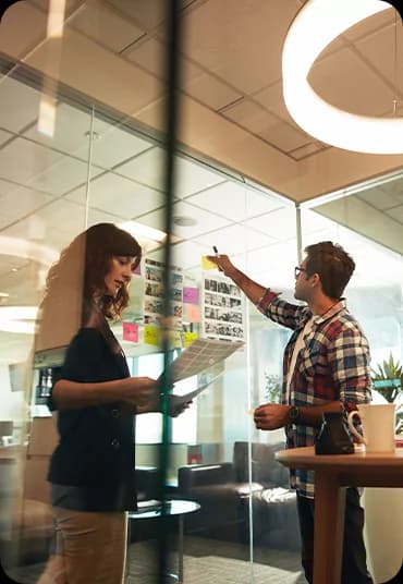 Team members discussing a project at a glass wall